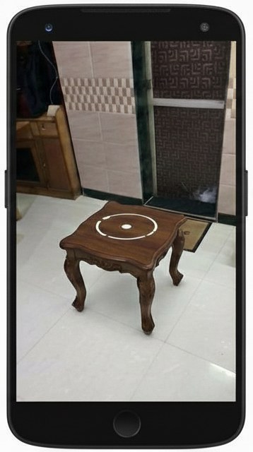 Markerless AR surface detection on an Android phone. The camera view shows a wooden table with a circular placement reticle detected on its surface.